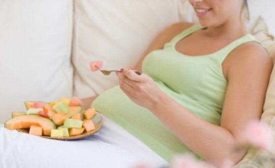 Foto de grávida comendo no sofá